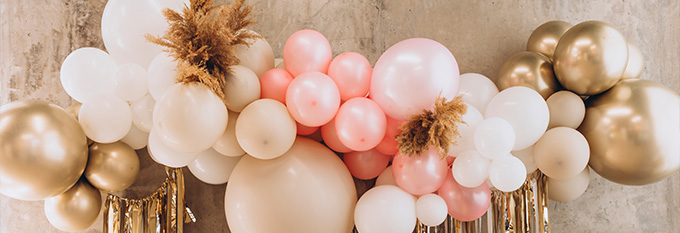 pastel pink and gold balloon decorations on a wall