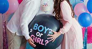 an expecting mother and father holding a balloon for a gender reveal party