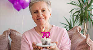 an older lady holding up a cupcake with the number 70 candles together